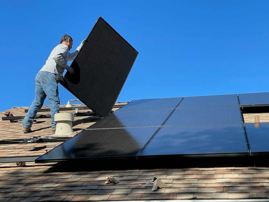 A technician fitting a solar panel on a roof